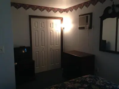 a bedroom with a bed and a mirror and a door at Fred's Inn Restaurant & Lodging in Norwich