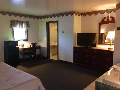 a bedroom with a bed and a mirror and a desk at Fred's Inn Restaurant & Lodging in Norwich