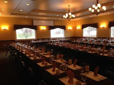 a conference room with tables and chairs and chandeliers at Fred's Inn Restaurant & Lodging in Norwich