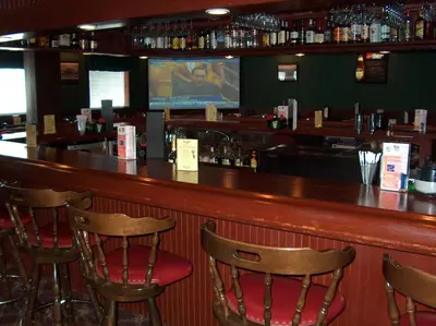a bar with chairs and a television in a restaurant at Fred's Inn Restaurant & Lodging in Norwich