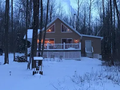 a house in the snow in the woods at Hidden Lakefront Retreat in Sherburne