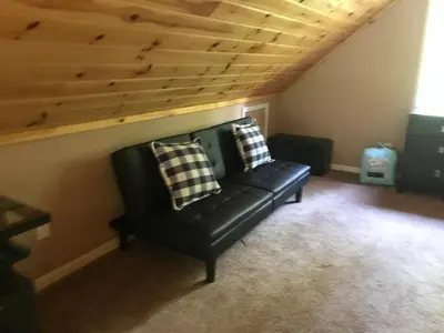 a black leather couch in a room with a wooden ceiling at Hidden Lakefront Retreat in Sherburne