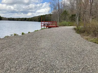 a red bench sitting on the side of a lake at Hidden Lakefront Retreat in Sherburne