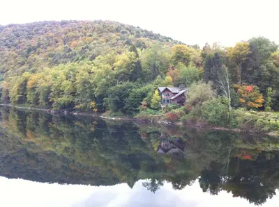 a house on a hill next to a river at A River Runs Through It in East Branch