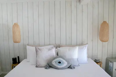 a bed with white pillows and a hat on it at The Surfside Hotel in Stratford