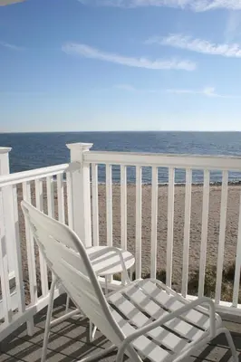 a white rocking chair sitting on a balcony overlooking the beach at The Surfside Hotel in Stratford