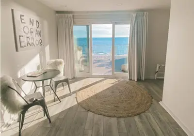 a living room with a table and a view of the ocean at The Surfside Hotel in Stratford