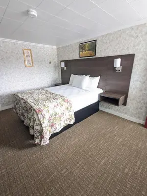 a hotel room with a large bed with a floral bedspread at Bennington Motor Inn in Bennington