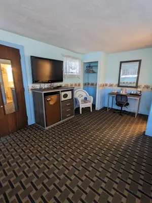 a living room with a flat screen tv and a desk at Bennington Motor Inn in Bennington
