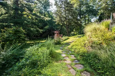 a stone path in a garden with trees and grass at Contemporary 3 Bedroom Apt with Sauna in Woods in Armonk