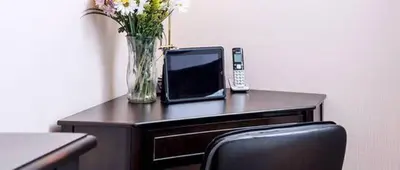 a desk with a vase of flowers and a telephone at Norwalk Inn & Conference Center in Norwalk