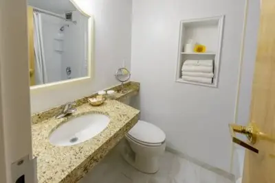 a bathroom with a sink and a toilet and a mirror at Norwalk Inn & Conference Center in Norwalk