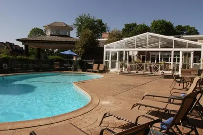a swimming pool with chairs and a pavilion at Norwalk Inn & Conference Center in Norwalk