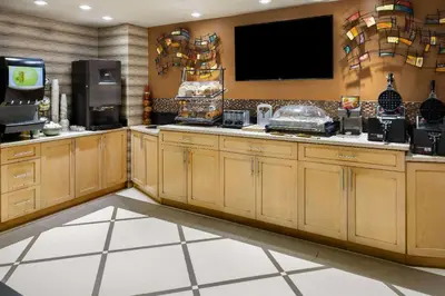 a kitchen with wooden cabinets and a flat screen tv at Ramada by Wyndham Bronx in Bronx