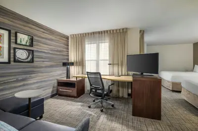 a hotel room with a bed and a desk with a television at Residence Inn by Marriott Albany Washington Avenue in Albany