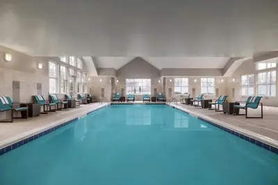 a large swimming pool with blue water in a building at Residence Inn by Marriott Albany Washington Avenue in Albany