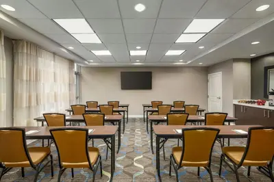 a conference room with tables and chairs and a screen at Residence Inn by Marriott Albany Washington Avenue in Albany
