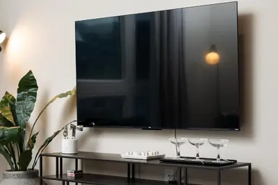 a flat screen tv on a wall with two wine glasses at Luxury Furnished Apartments by Hyatus Downtown at Yale in New Haven
