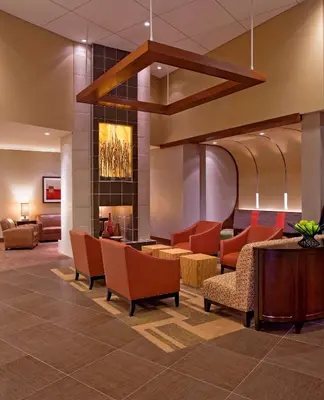 a lobby with orange chairs and a fireplace at Hyatt Place Milford/New Haven in Milford
