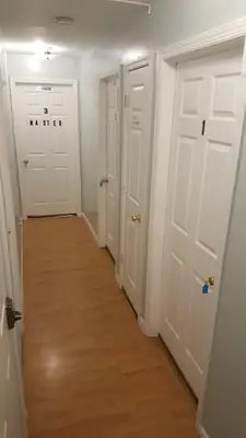 a hallway with three white doors and a wooden floor at 500 Estates LLC in Irvington