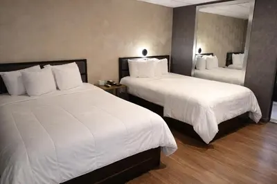a hotel room with two beds with white sheets at Cabana Hotel Yankee Stadium in Bronx