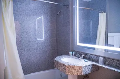 a bathroom with a sink and a shower with a mirror at Cabana Hotel Yankee Stadium in Bronx