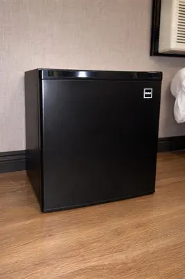 a black refrigerator sitting on top of a wooden floor at Cabana Hotel Yankee Stadium in Bronx