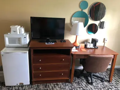 a hotel room with a desk with a microwave and a television at Howard Johnson by Wyndham Rocky Hill in Rocky Hill