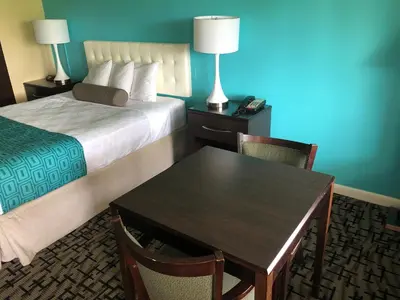 a hotel room with a table and a bed and a table and chairs at Howard Johnson by Wyndham Rocky Hill in Rocky Hill