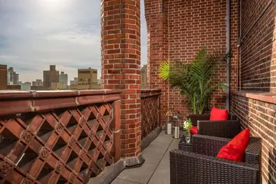 a balcony with red pillows and chairs on a brick building at NH Collection New York Madison Avenue in New York