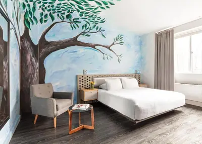 a bedroom with a bed and a tree mural at NU Hotel in Brooklyn