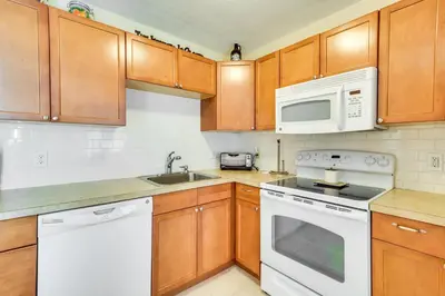 a kitchen with white appliances and wooden cabinets at Homey Windham Condo Hike and Ski the Catskill Mtns! in Windham