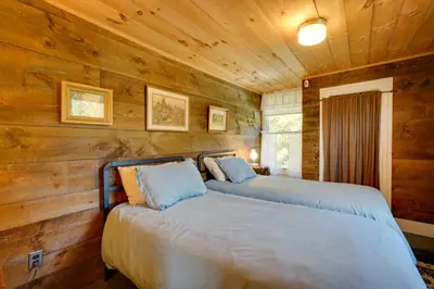 two beds in a room with wooden walls at Johns Farmhouse in Mount Snow on 120 Acres! in Whitingham