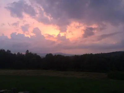 a sunset over a field with trees in the background at Johns Farmhouse in Mount Snow on 120 Acres! in Whitingham