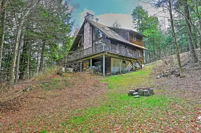 a large wooden house in the woods at Stamford Lakefront Home with Dock and Wraparound Deck! in Stamford