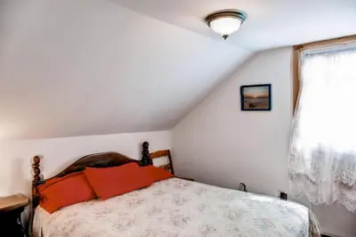 a bedroom with a bed with orange pillows and a window at 5 Mi to Cooperstown All Star Village Otego Home in Otego