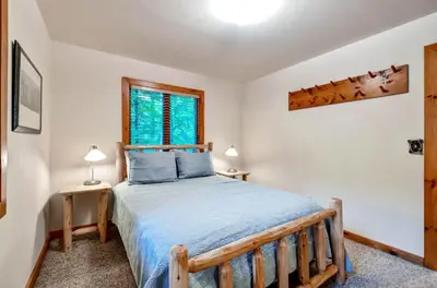 a bedroom with a wooden bed with blue pillows at Waterfront Highland Lake Home with Deck and Dock in Highland Lakes