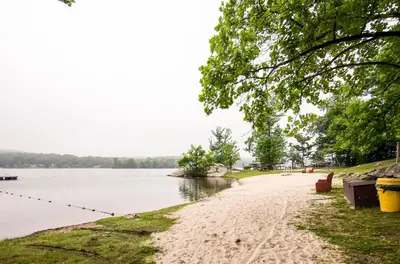 a sandy beach next to a body of water at Waterfront Highland Lake Home with Deck and Dock in Highland Lakes
