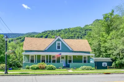 a blue house on the side of the road at Hunter Home with Fire Pit and Yard On Main Street! in Hunter