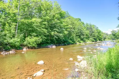 a river with rocks in the water and trees at Hunter Home with Fire Pit and Yard On Main Street! in Hunter
