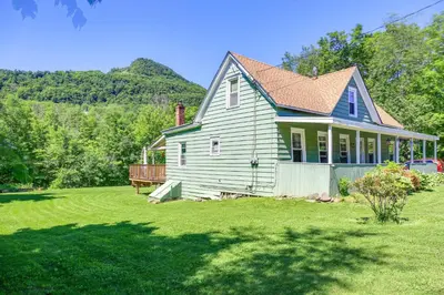 a house on a lawn with mountains in the background at Hunter Home with Fire Pit and Yard On Main Street! in Hunter