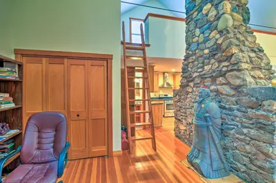 a living room with a stone fireplace and a ladder at Shelburne Studio Cabin with Spring-Fed Pool! in Shelburne