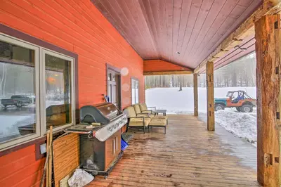 a covered porch of a home with a grill and chairs at Shelburne Studio Cabin with Spring-Fed Pool! in Shelburne