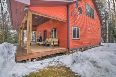 a house with a wooden deck in the snow at Shelburne Studio Cabin with Spring-Fed Pool! in Shelburne