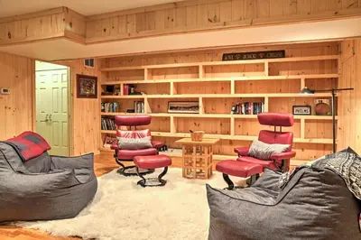 a living room with red chairs and book shelves at Berkshires Home on 11 Acres with Pond and 2 Fire Pits! in Becket