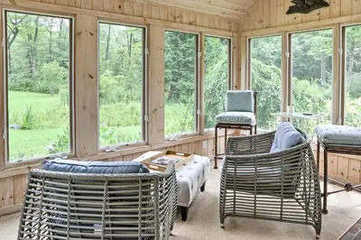 a screened in porch with chairs and windows at Berkshires Home on 11 Acres with Pond and 2 Fire Pits! in Becket