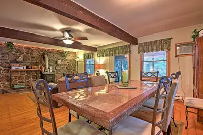a dining room with a table and a stone wall at 1 Mi to Lake Wallenpaupack Pocono Mountain Home! in Greentown