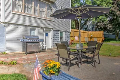 a table and chairs with an umbrella and a grill at Cozy Agawam Studio with Yard 2 Miles to Six Flags! in Agawam