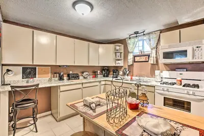a kitchen with white cabinets and a wooden table at Cozy Agawam Studio with Yard 2 Miles to Six Flags! in Agawam