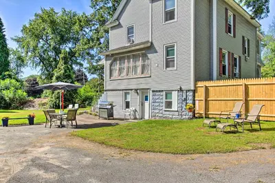 a house with chairs and an umbrella in the yard at Cozy Agawam Studio with Yard 2 Miles to Six Flags! in Agawam